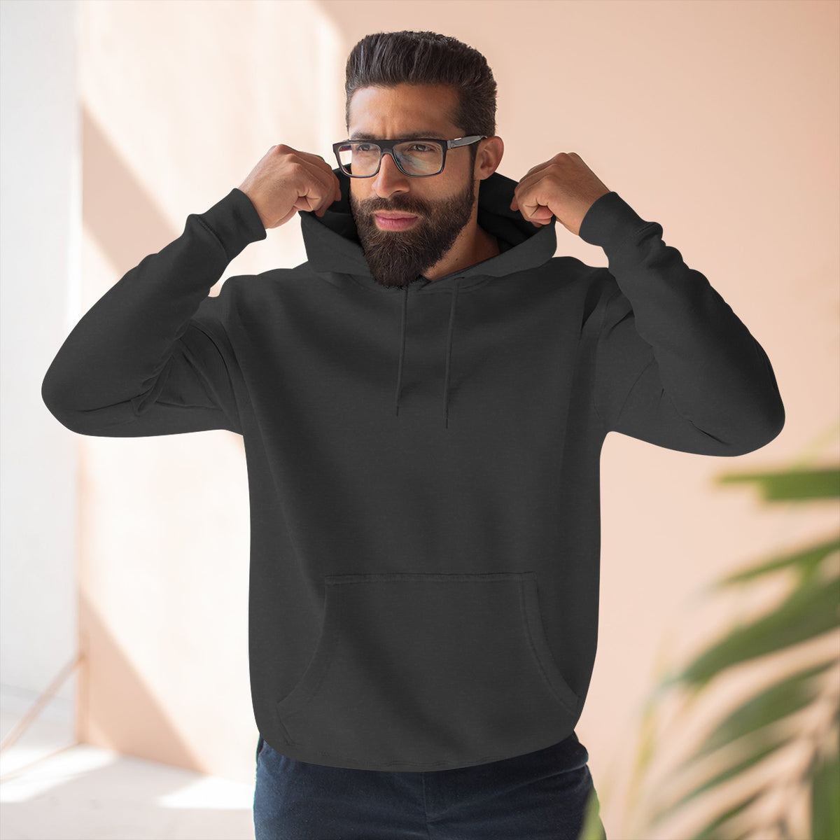 Man wearing a black hoodie with a small logo on a neutral background